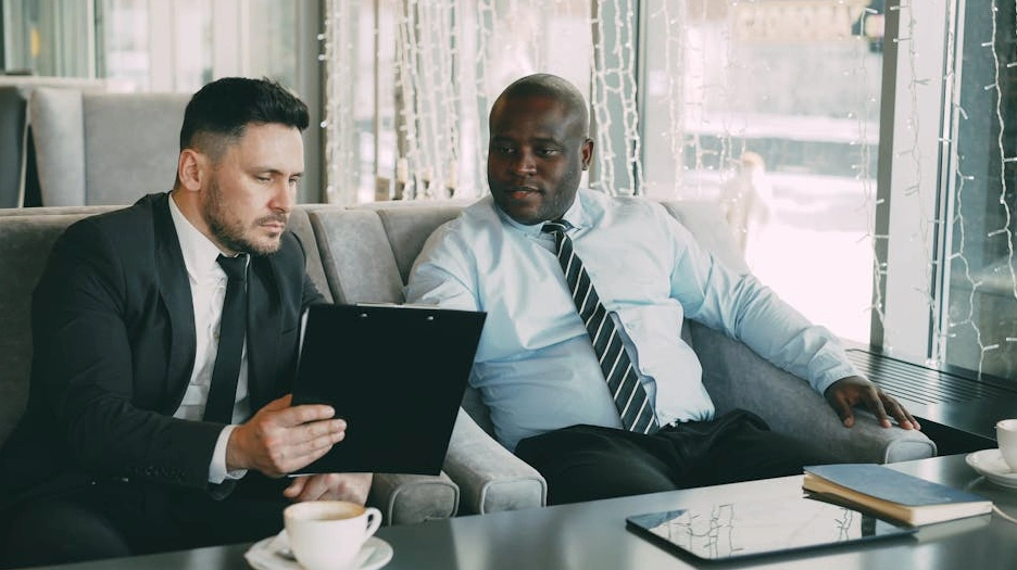 Два человека обсуждают документы за столом в современном офисе.